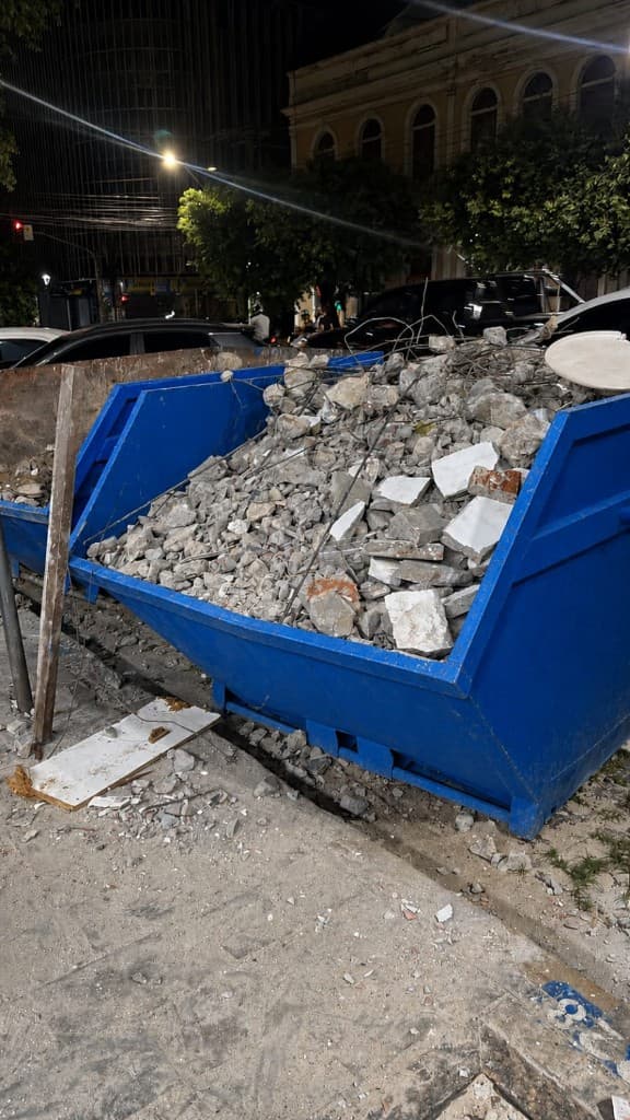 Caixa coletora azul da 3J cheia de entulho em calçada urbana de Manaus à noite